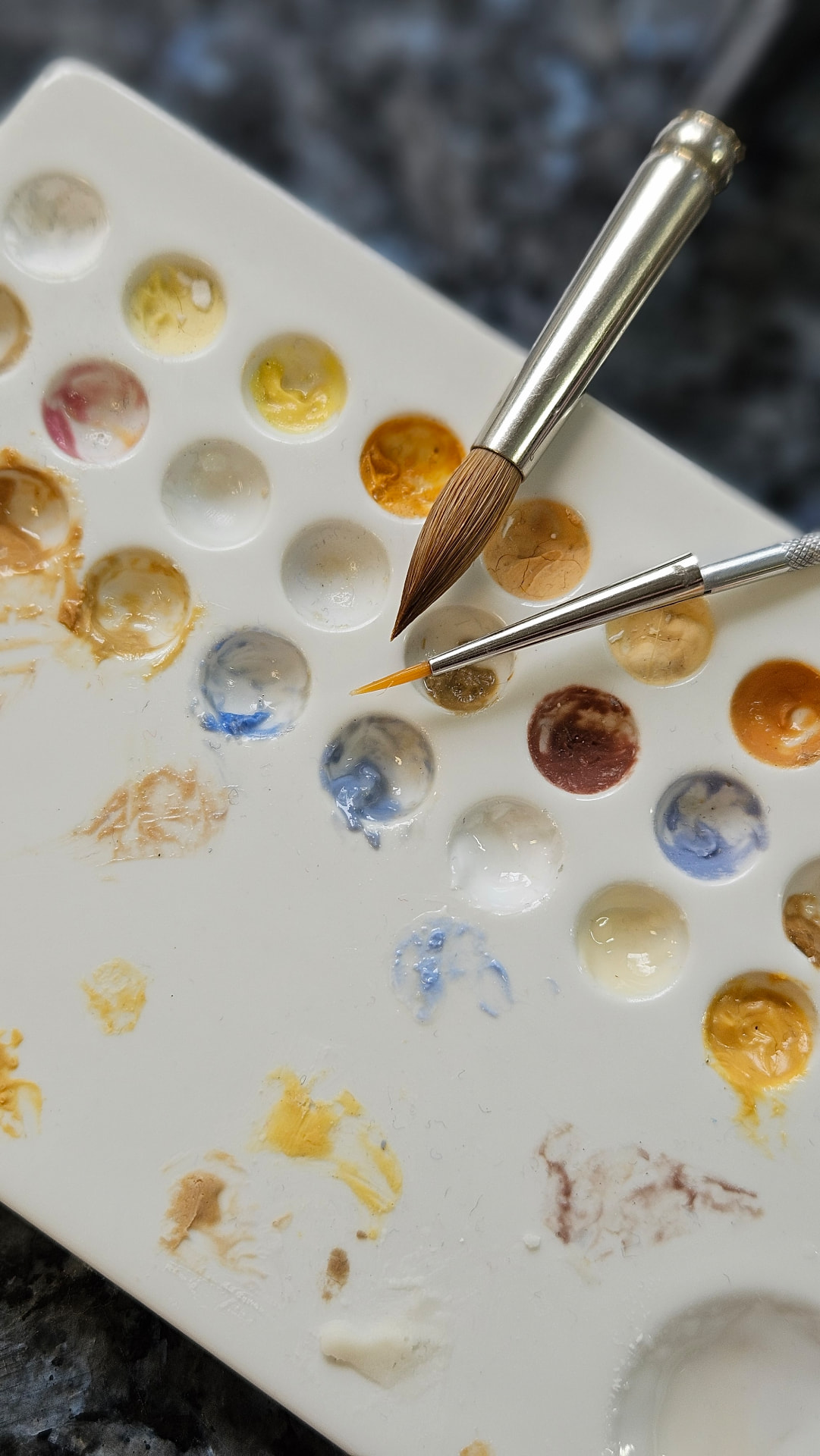 Farbpalette und feine Pinsel für die zahntechnische Ausarbeitung